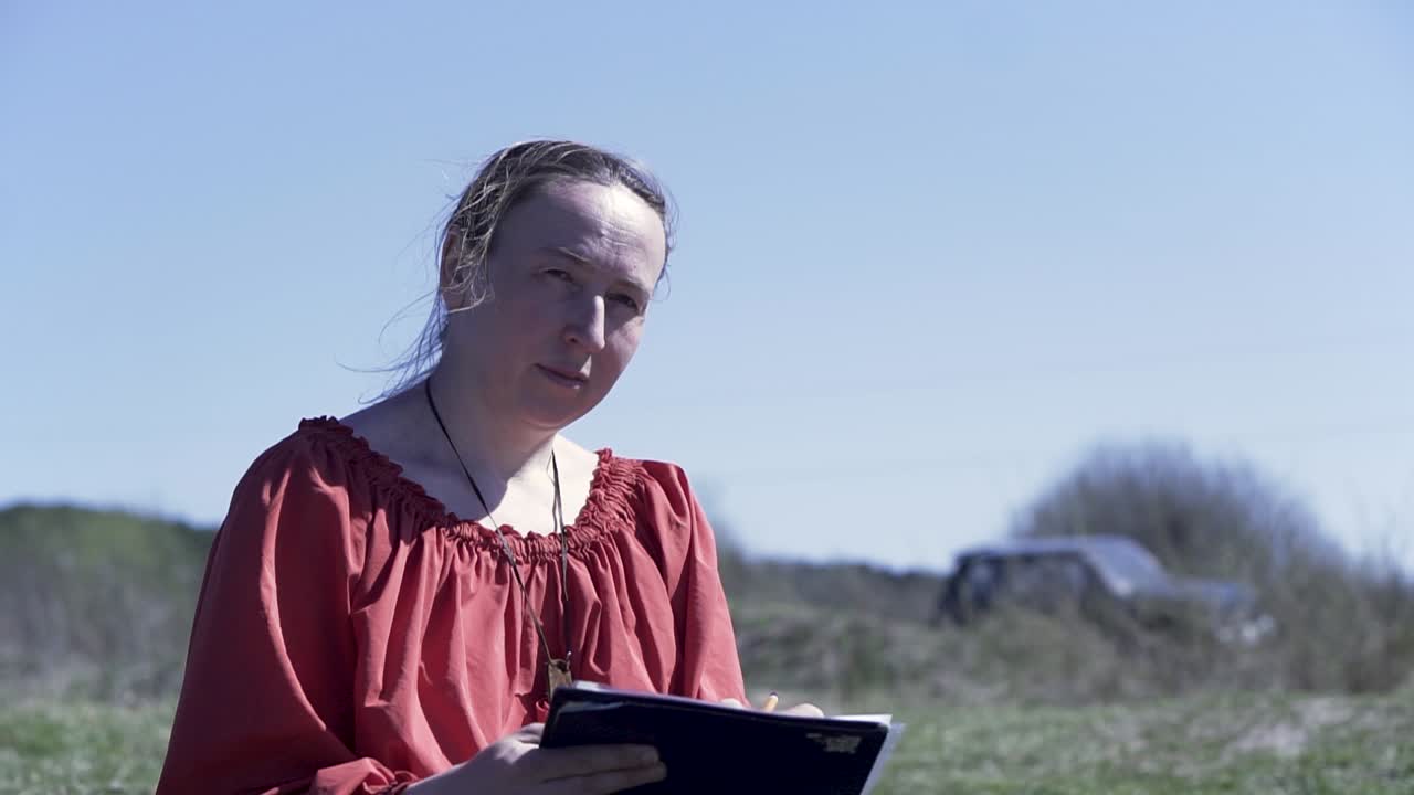 женщина пишет в блокноте на открытом воздухе