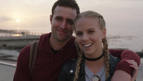 portrait of young happy couple embracing on beachfront smiling looking to camera