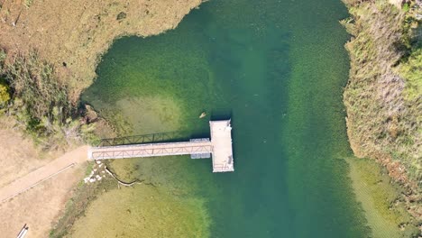 Starting-with-top-down-view-and-then-leveling-the-camera-and-circling-counter-clockwise-slowly-at-first-and-then-gaining-speed-showing-a-fishing-dock-in-a-small-inlet-on-a-lake