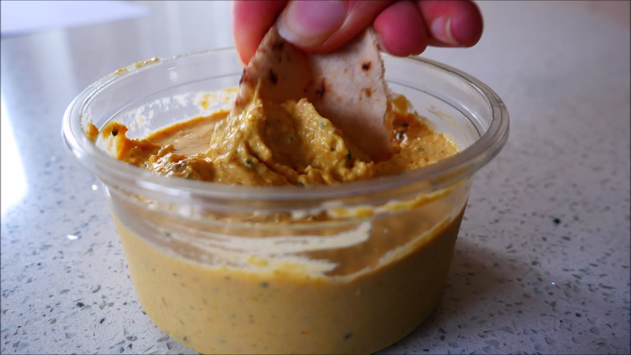 Pitta bread dipped into houmous dip. Food