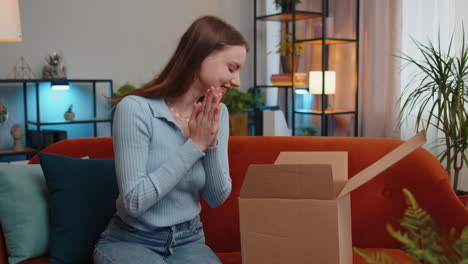 Happy-young-woman-shopper-unpacking-cardboard-box-delivery-parcel-online-shopping-purchase-at-home