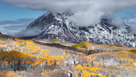 Kebler-Pass,-Filmische-Luftaufnahme,-Drohne,-Crested-Butte,-Gunnison,-Colorado,-Jahreszeiten-Kollidieren,-Frühherbst,-Espenbaum,-Rot,-Gelb,-Orange,-Wald,-Winter,-Erster-Schnee,-Pulver,-Felsiger-Berggipfel,-Unbefestigte-Straße,-Rückwärtsbewegung