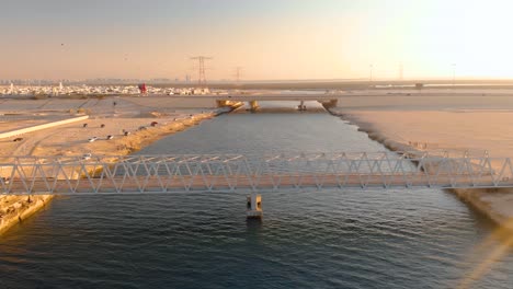 drone flies over epic iron bridge in barren abu dhabi setting during sunset, aerial