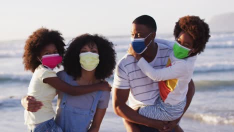 Portrait-of-african-american-family-wearing-face-masks-at-the-beach