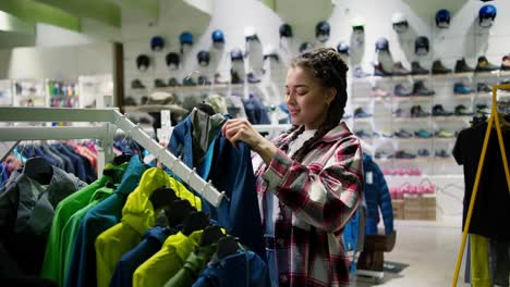Woman-in-outdoor-clothing-store-chooses-wind-down-jackets