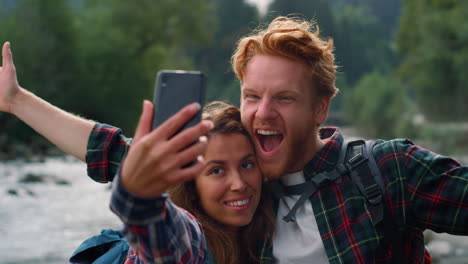 man and woman taking selfie on phone. friends making funny faces on camera