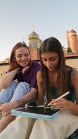 two young women collaborating on digital art project outdoors