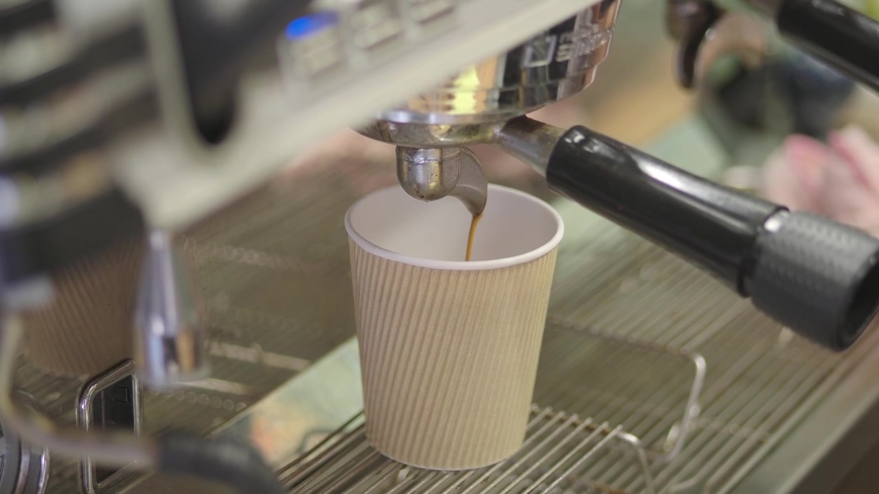 Caffè espresso versato in una tazza di carta da una macchina da caffè