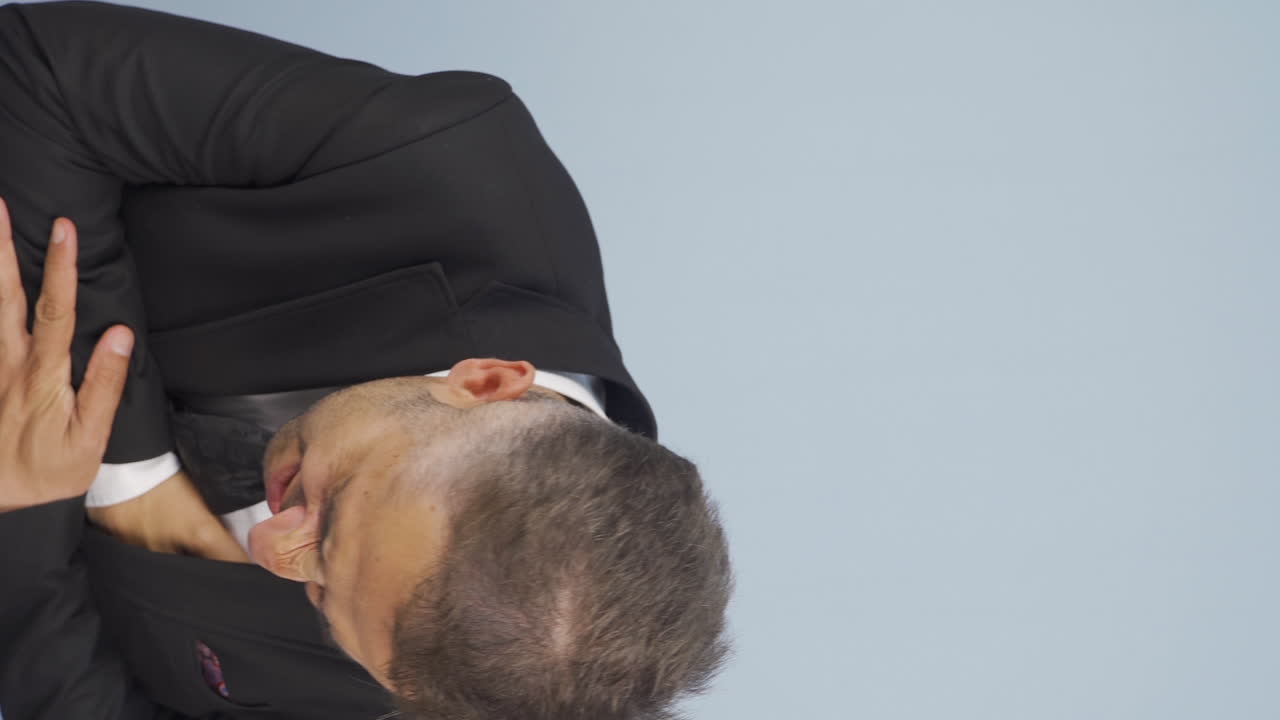 심장마비를 겪고 있는 사업가의 수직 영상입니다.