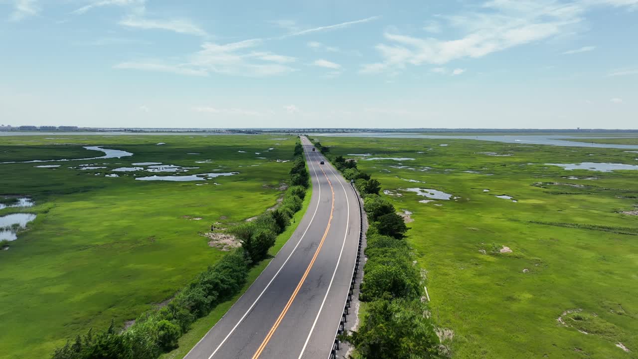 Aerial establishing shot of Main Street between Waters, marsh and wetland of New England. Wildwood in New Jersey. Summer day with Atlantic Ocean. Car driving on intersection. Wide shot