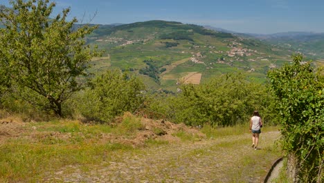 Toma-Panorámica-Con-Una-Chica-Caminando-Por-Un-Sendero-Salvaje-En-El-Valle-Del-Duero-En-Portugal