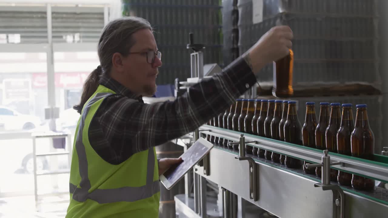 Caucasian man checking bottles of beer at a microbrewery