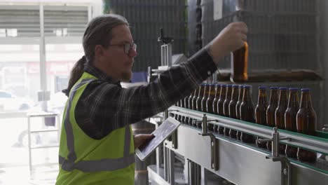 caucasian man checking bottles of beer at a microbrewery