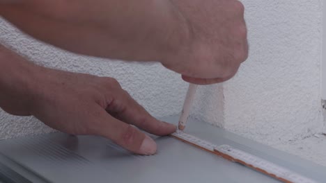 craftsman uses a pencil to mark a cut with a folding rule on a metal plank