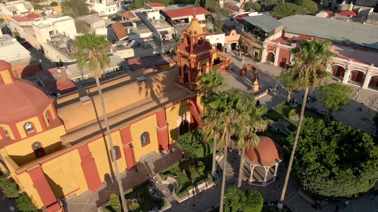 vista aérea del templo de san sebastián y turistas en la plaza principal de bernal, querétaro, méxico - disparo de drone