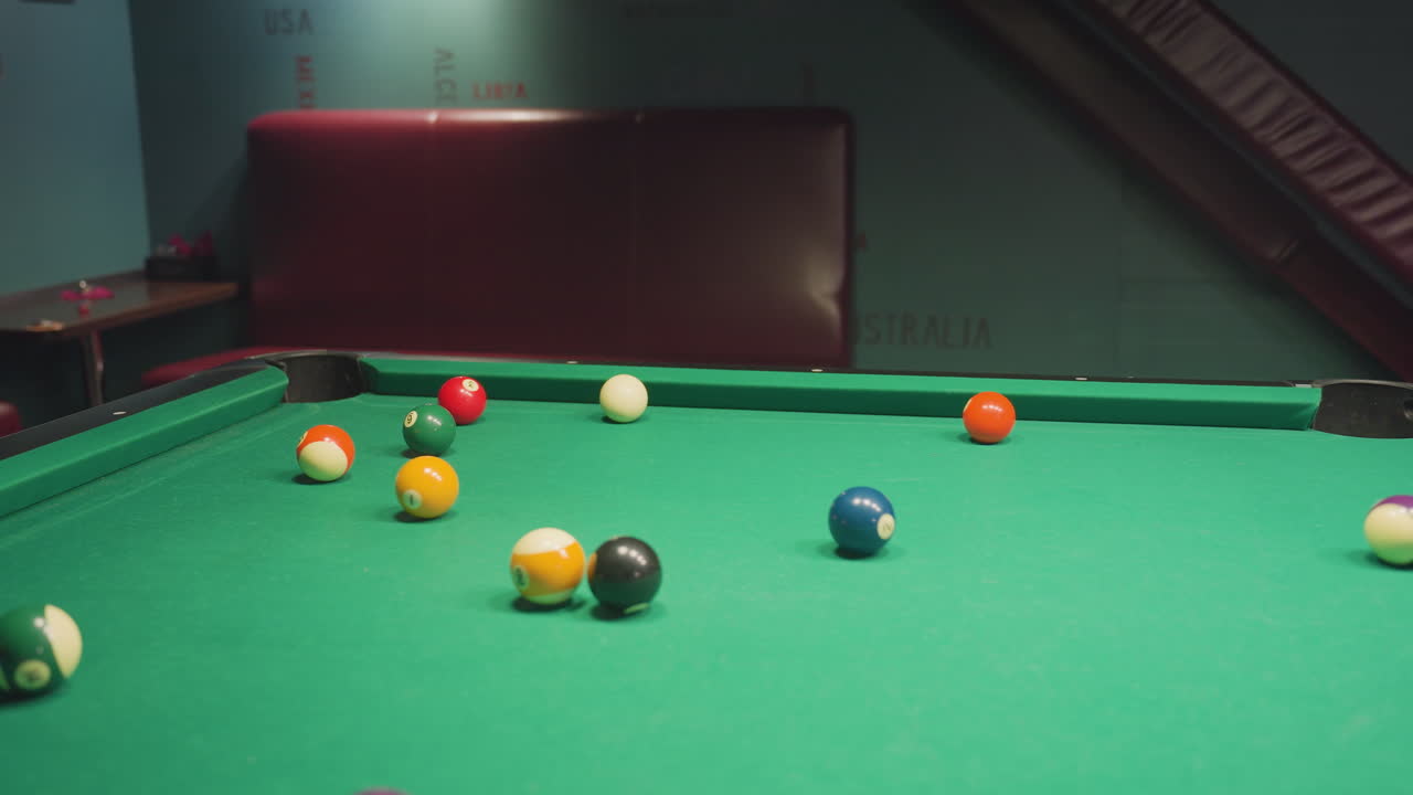 Billiard balls arranged on green pool table, slightly scattered after triangle rack is removed. Close-up shot captures vibrant colors and precise positioning before break shot in casual