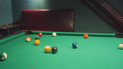 billiard balls arranged on green pool table, slightly scattered after triangle rack is removed. close-up shot captures vibrant colors and precise positioning before break shot in casual