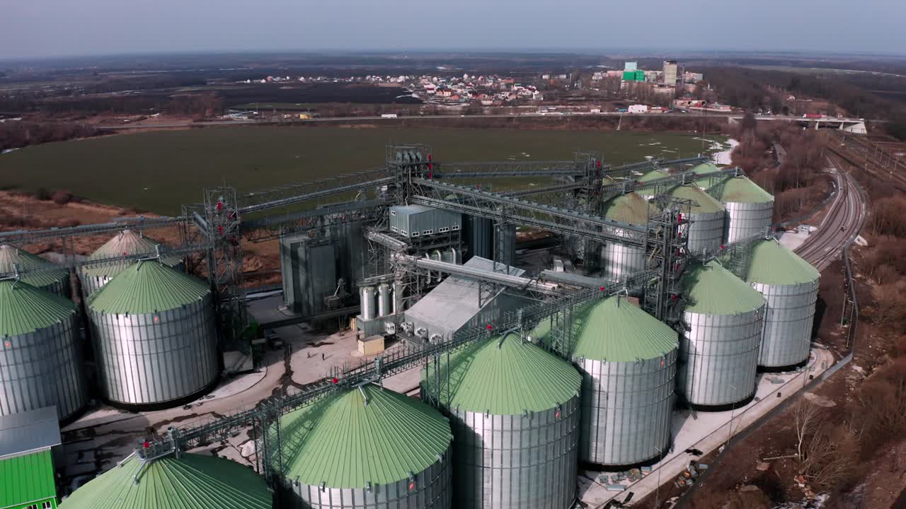 Metal silos on field aerial view. Large containers for storing and processing grains. Silver grain elevators in farmland. Storage tank view from above. Silo with grain.