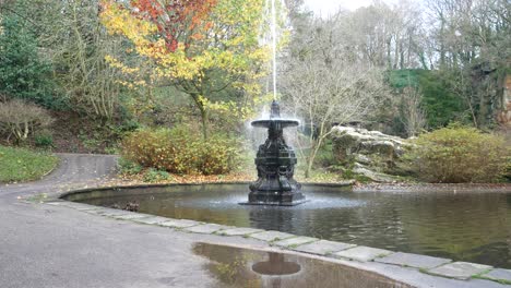 autumnal foliage ornate english fountain sprinkle spray in landmark historic garden landscape