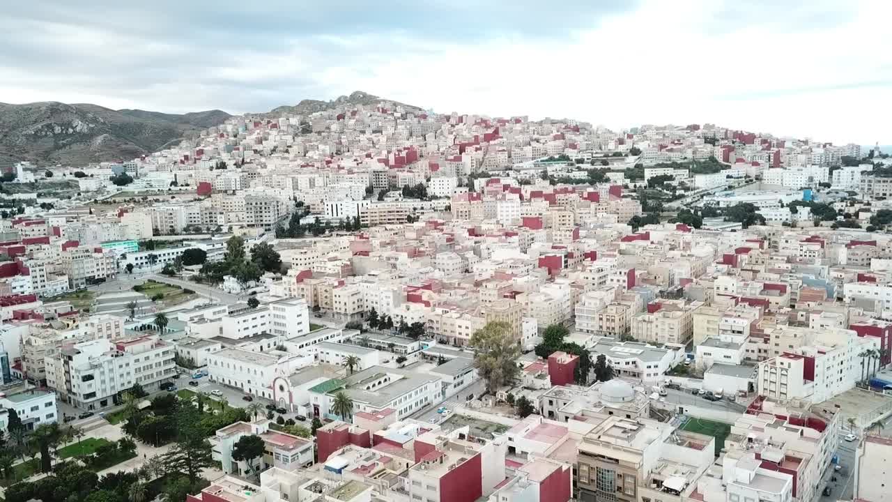 Drone footage capturing the urban sprawl of Al Hoceima city adapting to the rugged topography of the Rif Mountain slopes in Northern Morocco