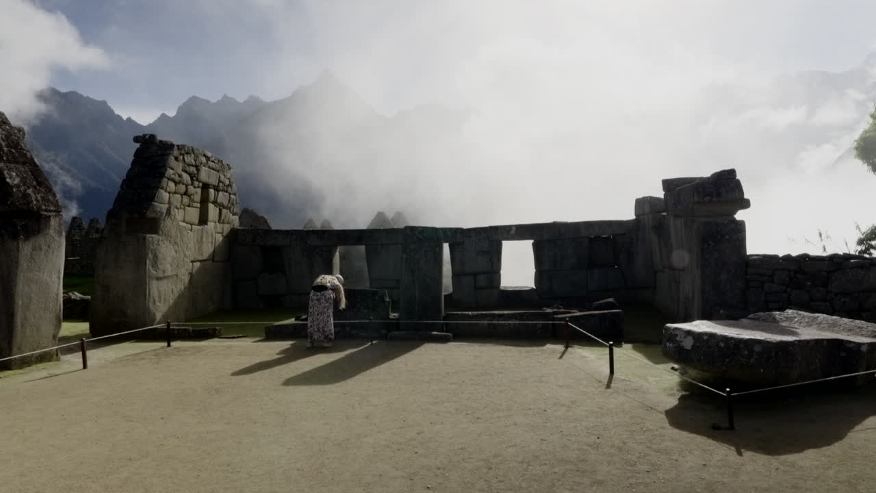 Tourist woman in dress walks inside Machu Picchu ruins and takes photos. Traveler, explorer in Peru