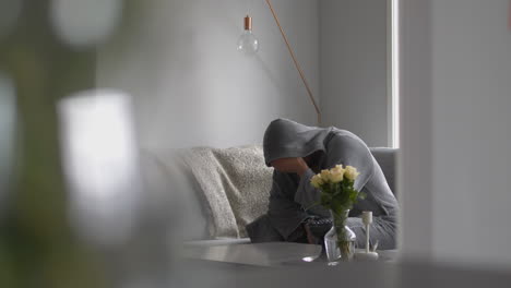 depressed idle man in housecoat covers face with hands, dolly shot