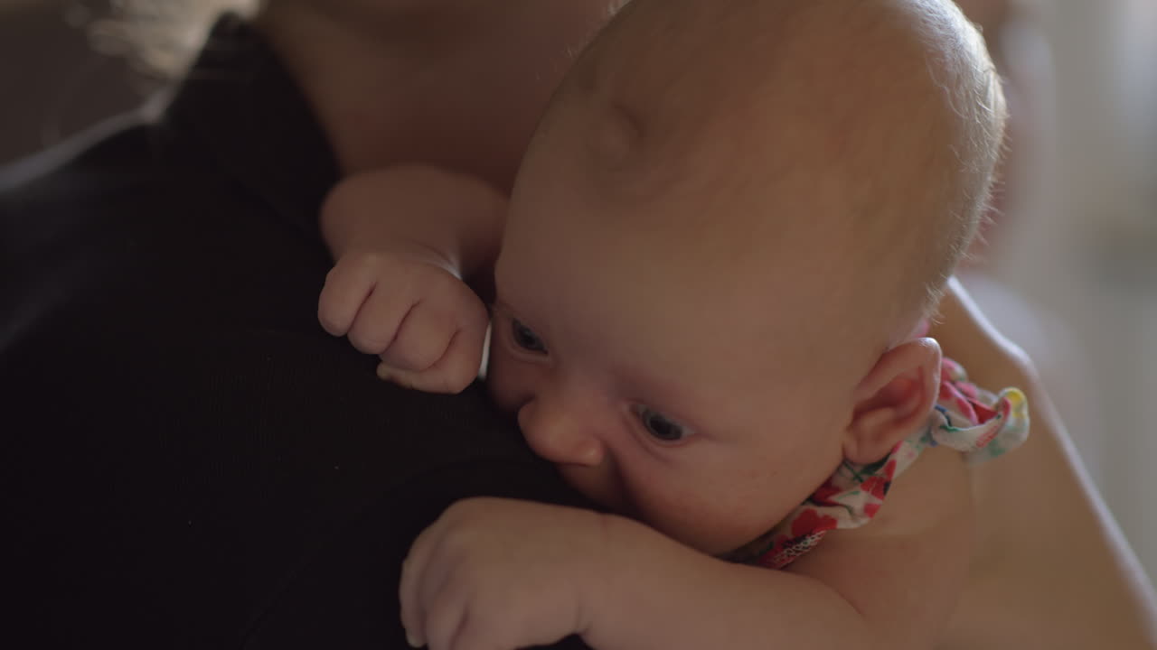 두 달 된 아기 소녀가 어머니의 어깨에