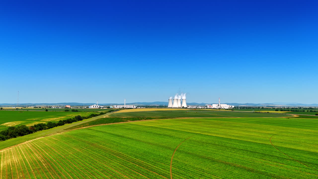 Distancing from a large industrial factory working in the countryside. Plant pipes produce white smoke. Aerial view