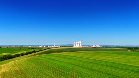 distancing from a large industrial factory working in the countryside. plant pipes produce white smoke. aerial view