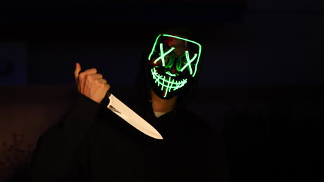 a scary slasher killer in a generic anonymous halloween horror mask pulling a knife on his murder victim