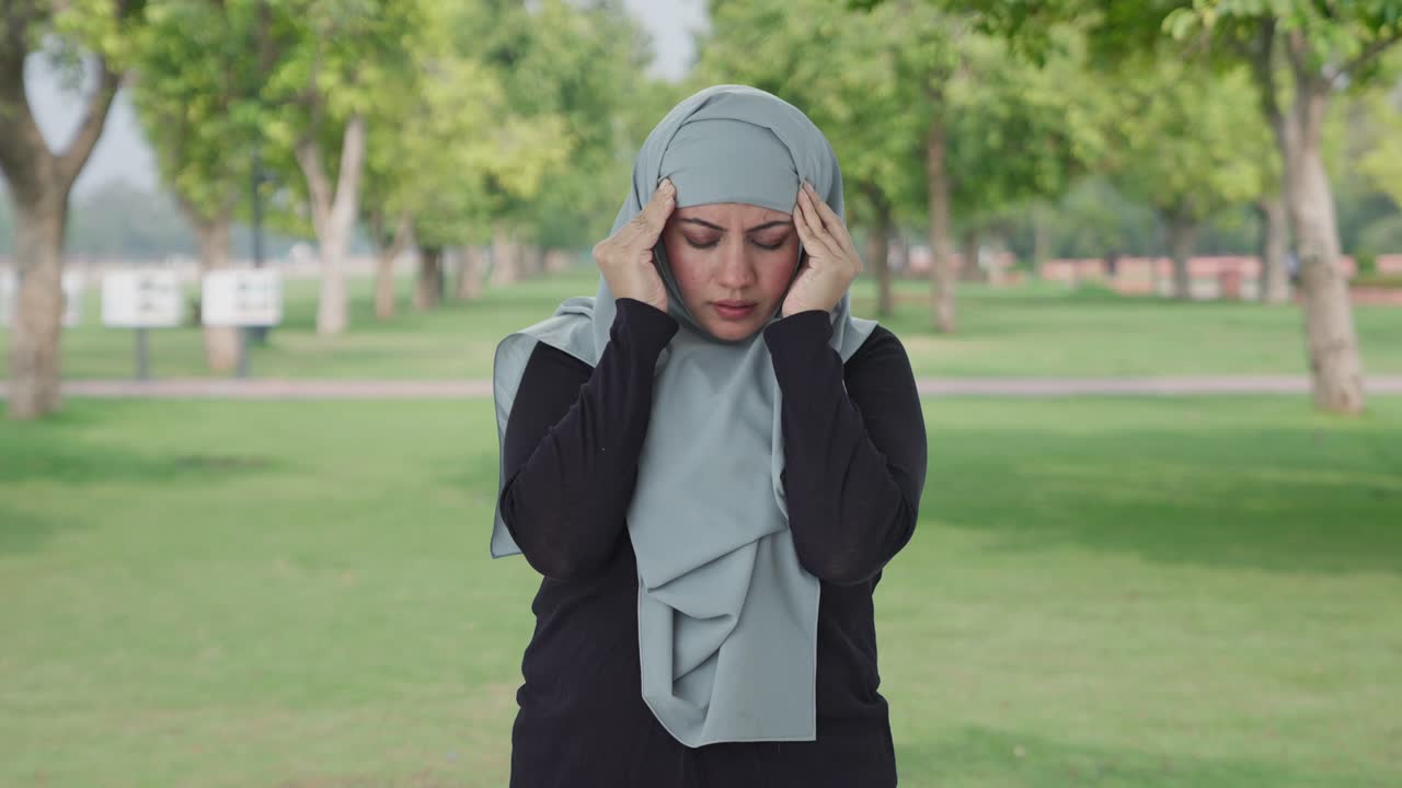 Wanita Muslim sakit menderita Sakit Kepala di taman