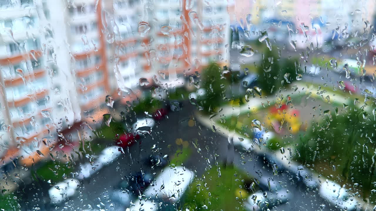 Rainy day from the window of high-rise building. Window covered with drops of water.