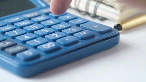 person pressing a button on a blue calculator