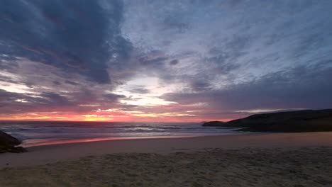 Lapso-De-Tiempo-Del-Amanecer-Desde-Antes-De-Que-El-Sol-Aparezca-Justo-Después-En-La-Playa-Del-Diablo-De-Arpoador-En-Río-De-Janeiro,-Brasil,-Con-Un-Intenso-Esquema-De-Colores-Cambiantes-Que-Se-Refleja-En-Las-Olas-Entrantes