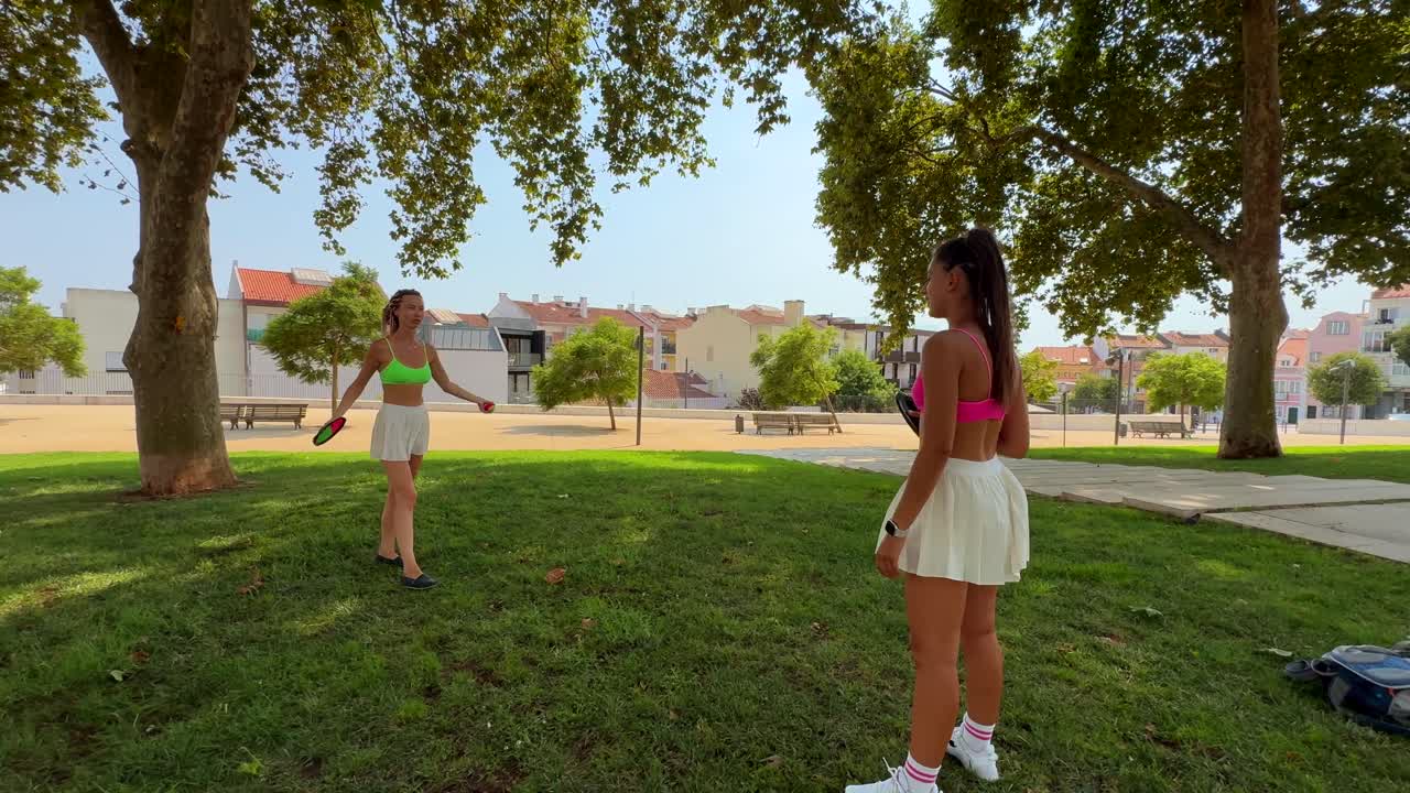 Two women playing tennis in a park