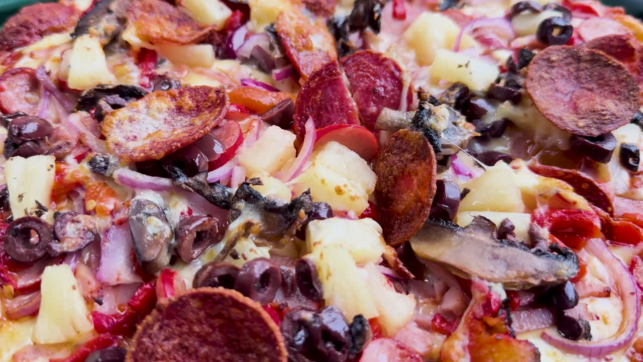 una pizza gira, mostrando varios ingredientes