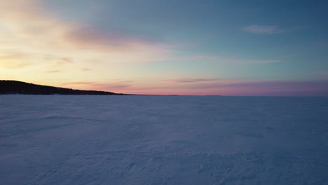 Flying-drone-above-a-frozen-lake-in-canada-at-golden-hour