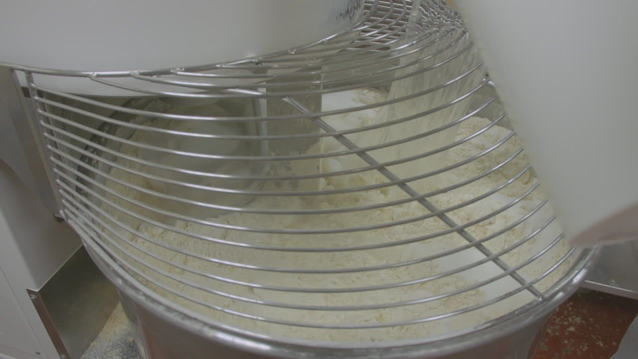 Wide slow mo of industrial food mixer turned on. Buckets of water are added to the mix