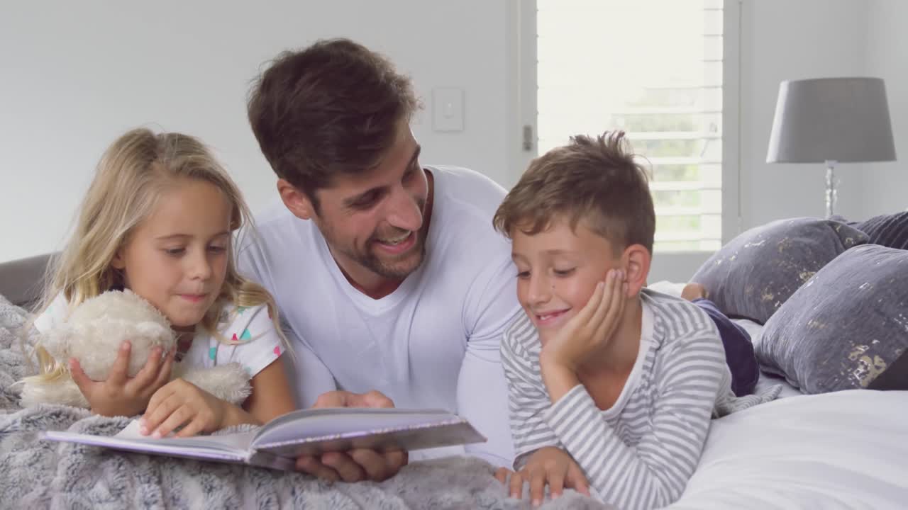 padre con sus hijos leyendo un libro de cuentos en el dormitorio en casa 4k