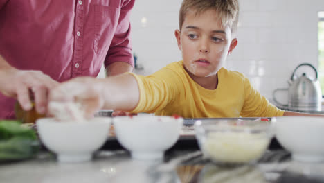 Feliz-Abuelo-Caucásico-Y-Nieto-Haciendo-Pizza-En-La-Cocina,-Cámara-Lenta