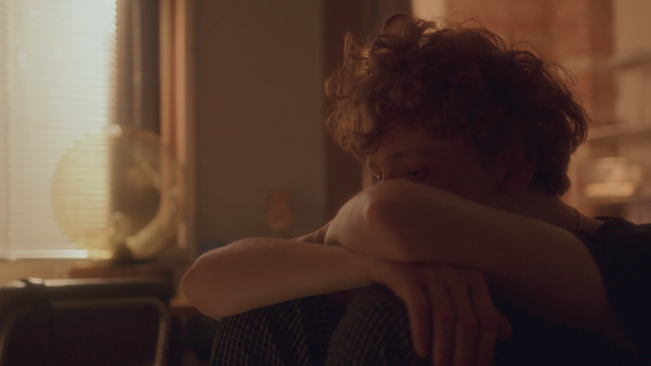 머리가 접힌 팔에 기대어 앉아 있는 불행한 젊은 남자