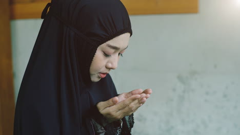 portrait of an asian muslim women in a daily prayer at home reciting surah al-fatiha passage of the qur'an in a single act of sujud called a sajdah or prostration