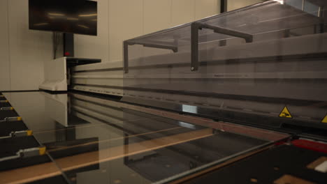 automated laminated glass cutting machine operating on modern office showcase display