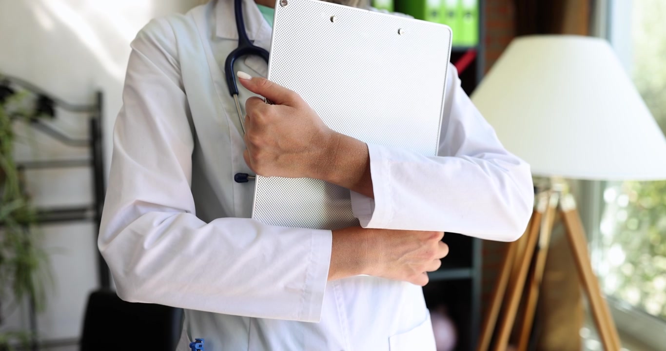 Uma mulher é médica com uma pasta branca nas mãos