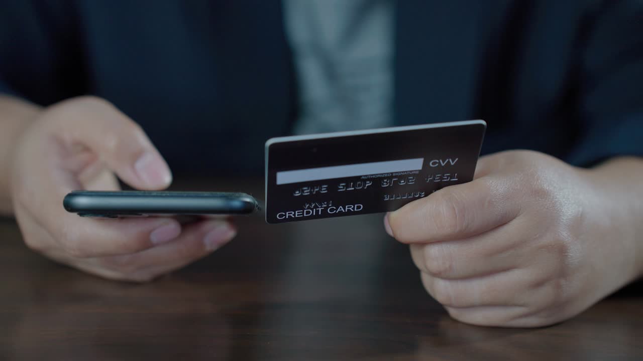 banca en línea con teléfono inteligente para comprar. manos sosteniendo una tarjeta de crédito mientras presiona el número de identificación en el móvil desde la tarjeta de crédito para comprar en línea. pago fácil usando móvil. imágenes b roll movimiento lento 4k.