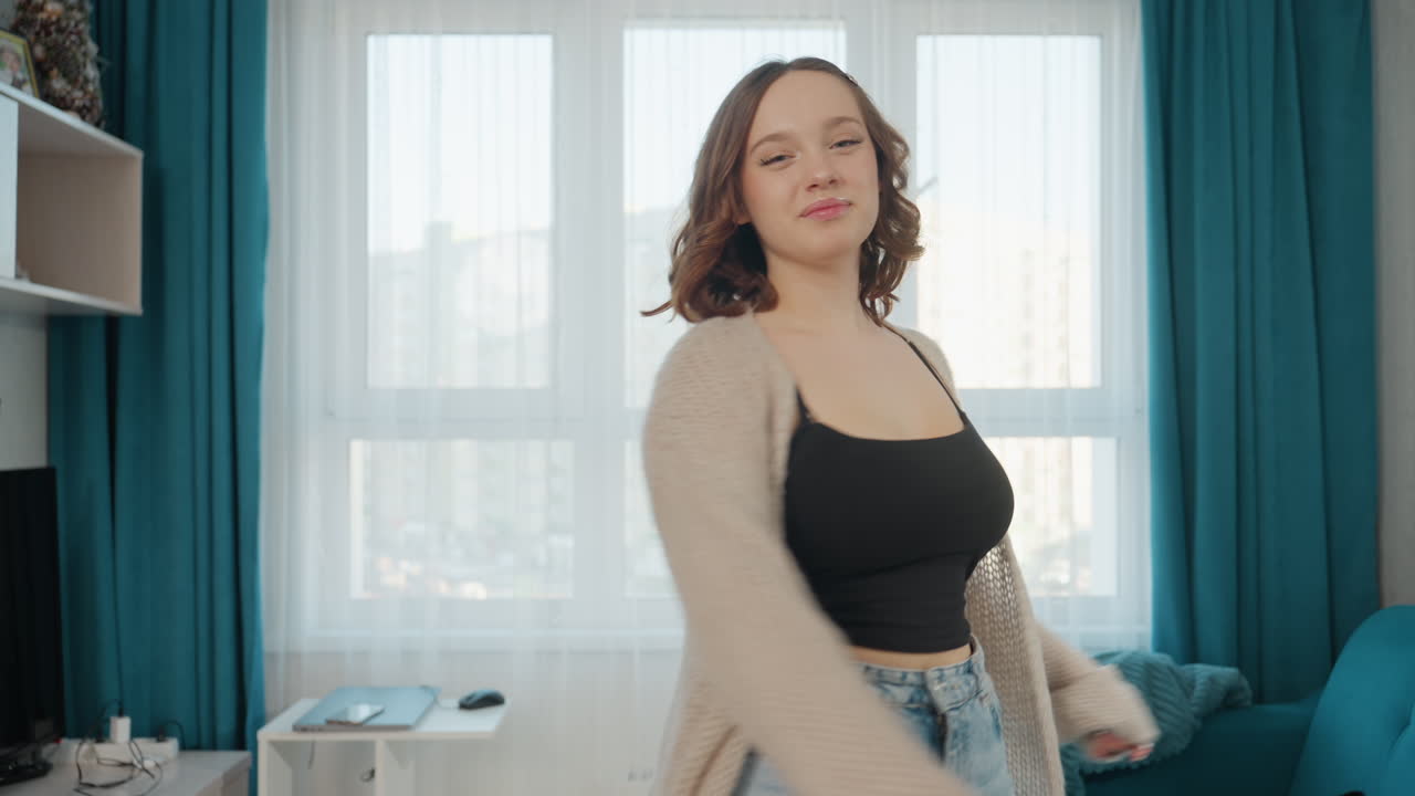 Sunlit Room Captures Cheerful Woman Stretching, Woman In Jeans Smiles And Extends Arm In Bright Living Room, Casual Woman With Playful Expression Performs Stretch In Sunlit Home Environment