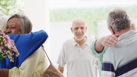 Happy-couple-greeting-group-of-diverse-senior-male-and-female-friends-at-front-door,-slow-motion