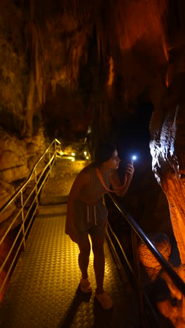 Woman Exploring a Cave with a Flashlight