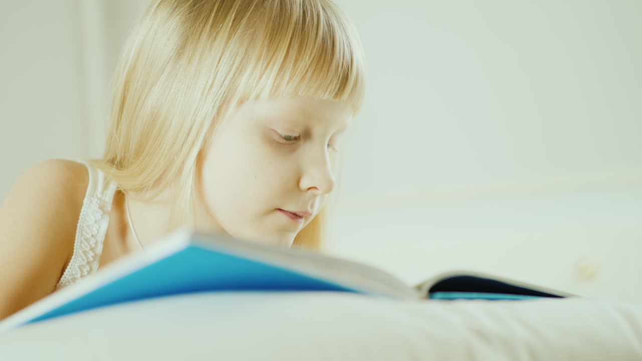 Bambina bionda che legge un libro a letto - Video 4K 26
