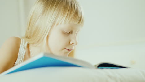 niña rubia leyendo un libro en la cama 4k video 26